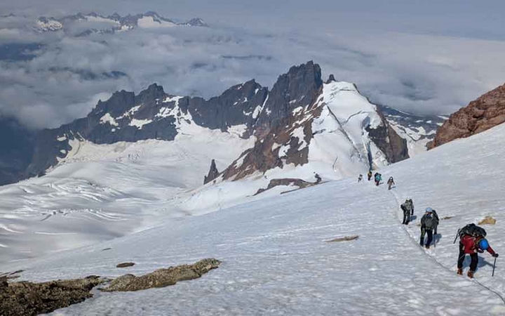 a group of students on a mountaineering course traverse a snowy mountainous landscape